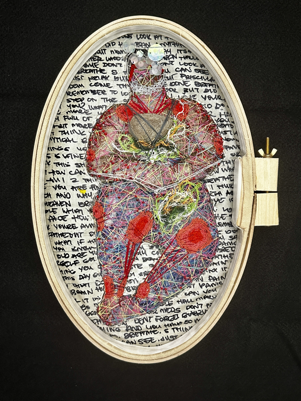 The reverse side of the previous piece. The figure is covered in crisscrossed neon lines, and has red knotted patches surrounding their joints. There are iridescent sequins covering the figure’s head and silver thread tightly knotting over the jaw. Red beads dot the figure's limbs. The background is full of fragments of handwritten text on duct tape that is collecting debris. 